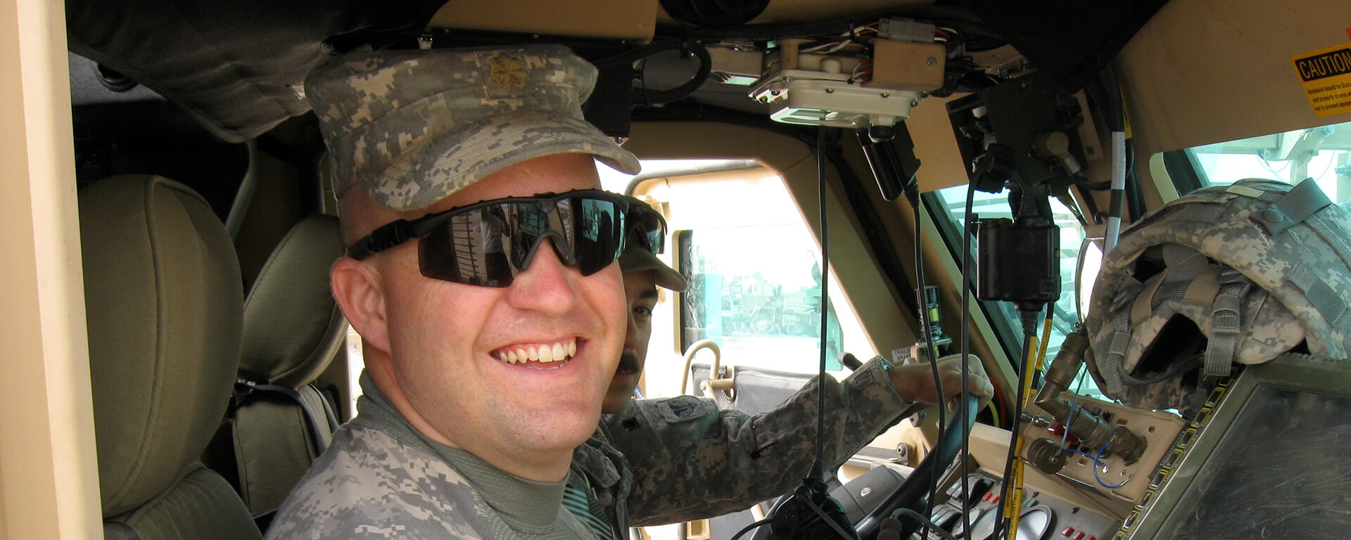 Chris, a Tech leader at Capital One, sits in a military vehicle in his digis while deployed in Afghanistan